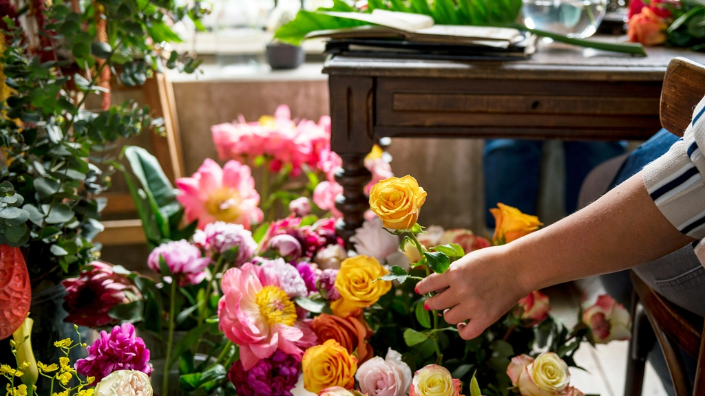 A hand picks put a flower from a colorful array