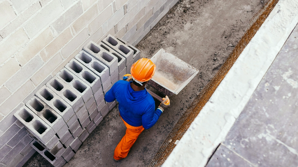 An overhead view of a construction worker in a hard hat pushing a wheelbarrow