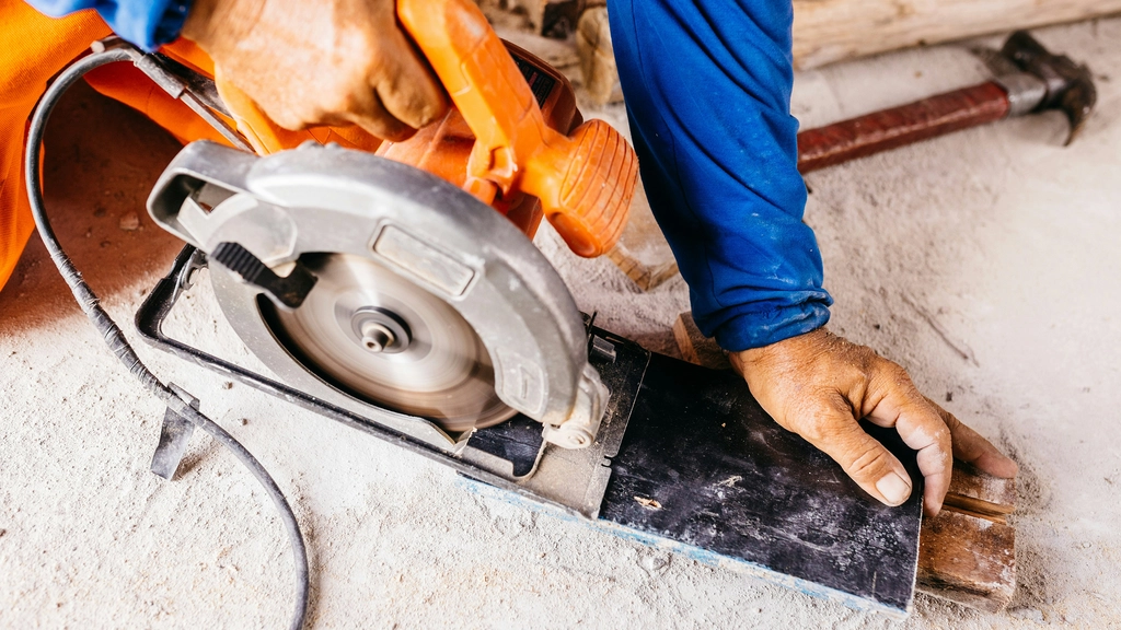 A hand holding a power saw to cut through stone