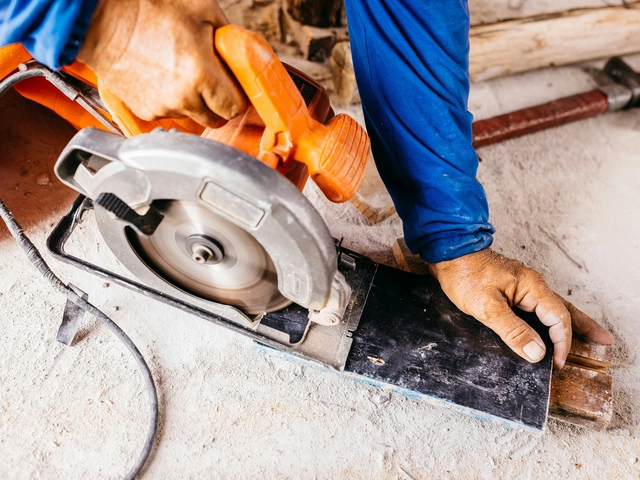 A hand holding a power saw to cut through stone
