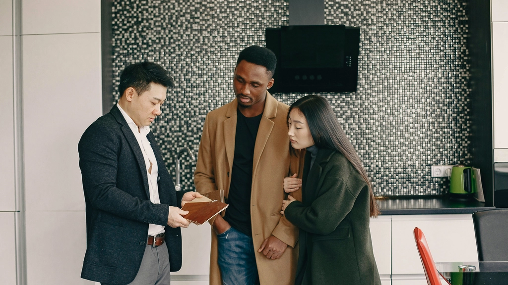 Three people in work clothes look at a document together