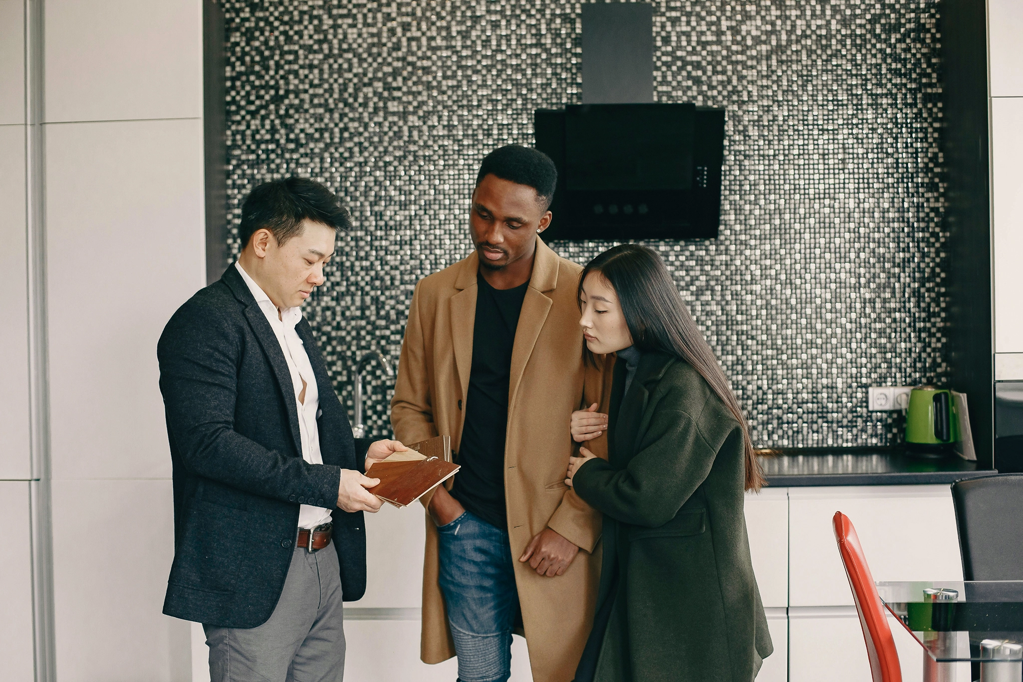 Three people in work clothes look at a document together