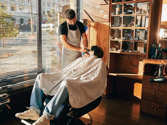 A barber prepares to cut his clients hair, who is seated in a barber chair