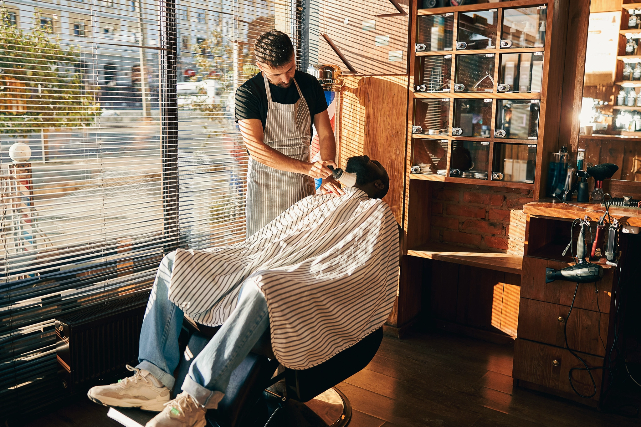 A barber prepares to cut his clients hair, who is seated in a barber chair
