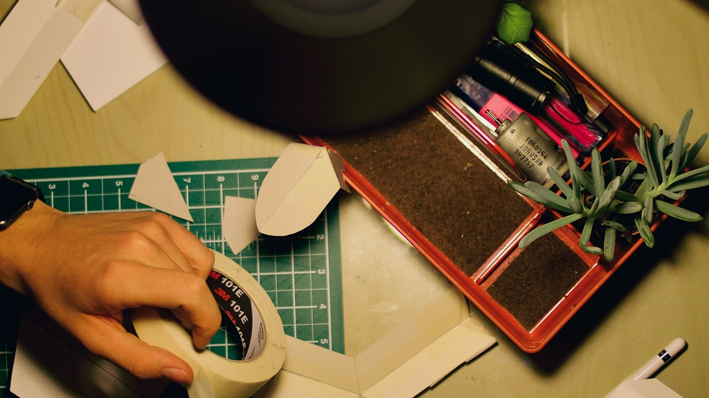 An overhead view of a desk with a light and a person's hands working with objects