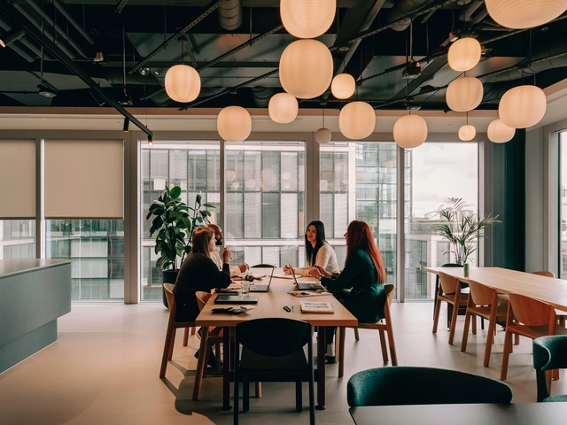 people sitting at a table under round overhead lights