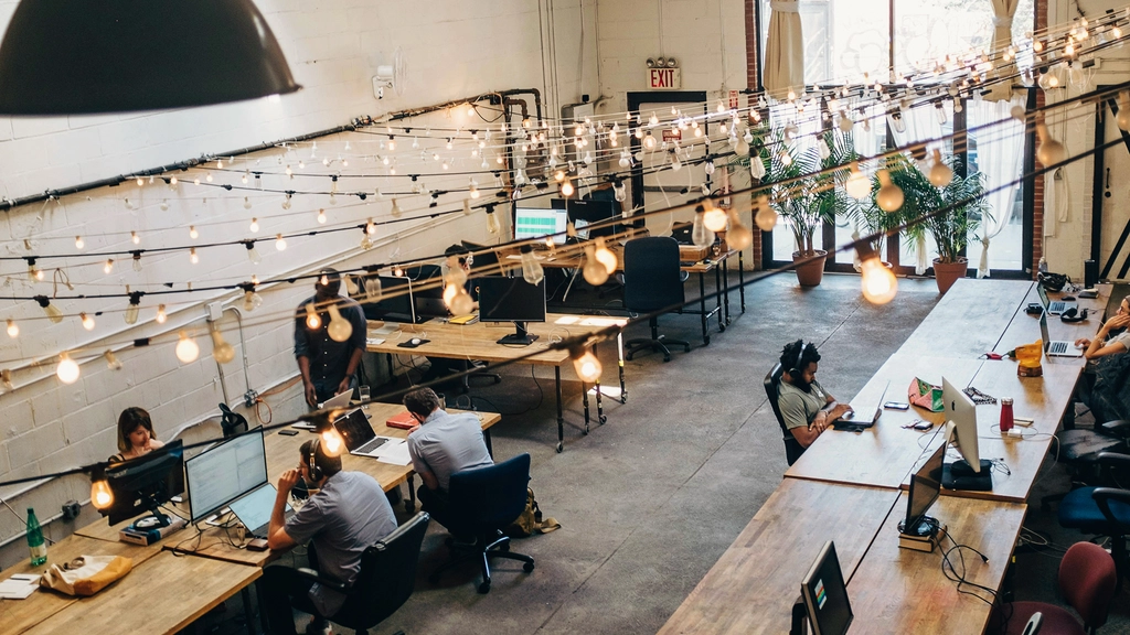 An open workspace with rows of tables and workers on laptops