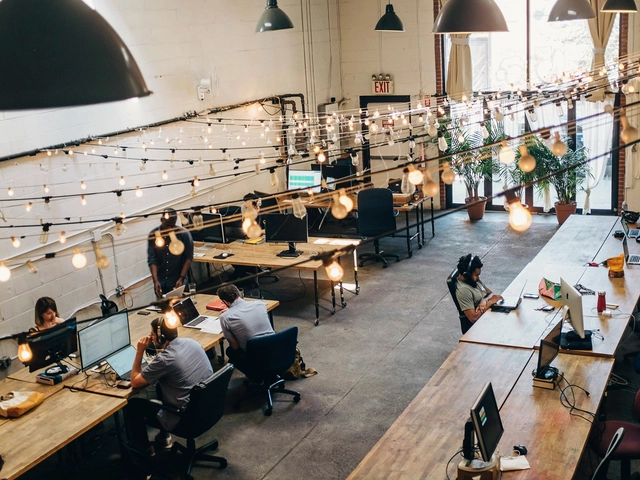 An open workspace with rows of tables and workers on laptops