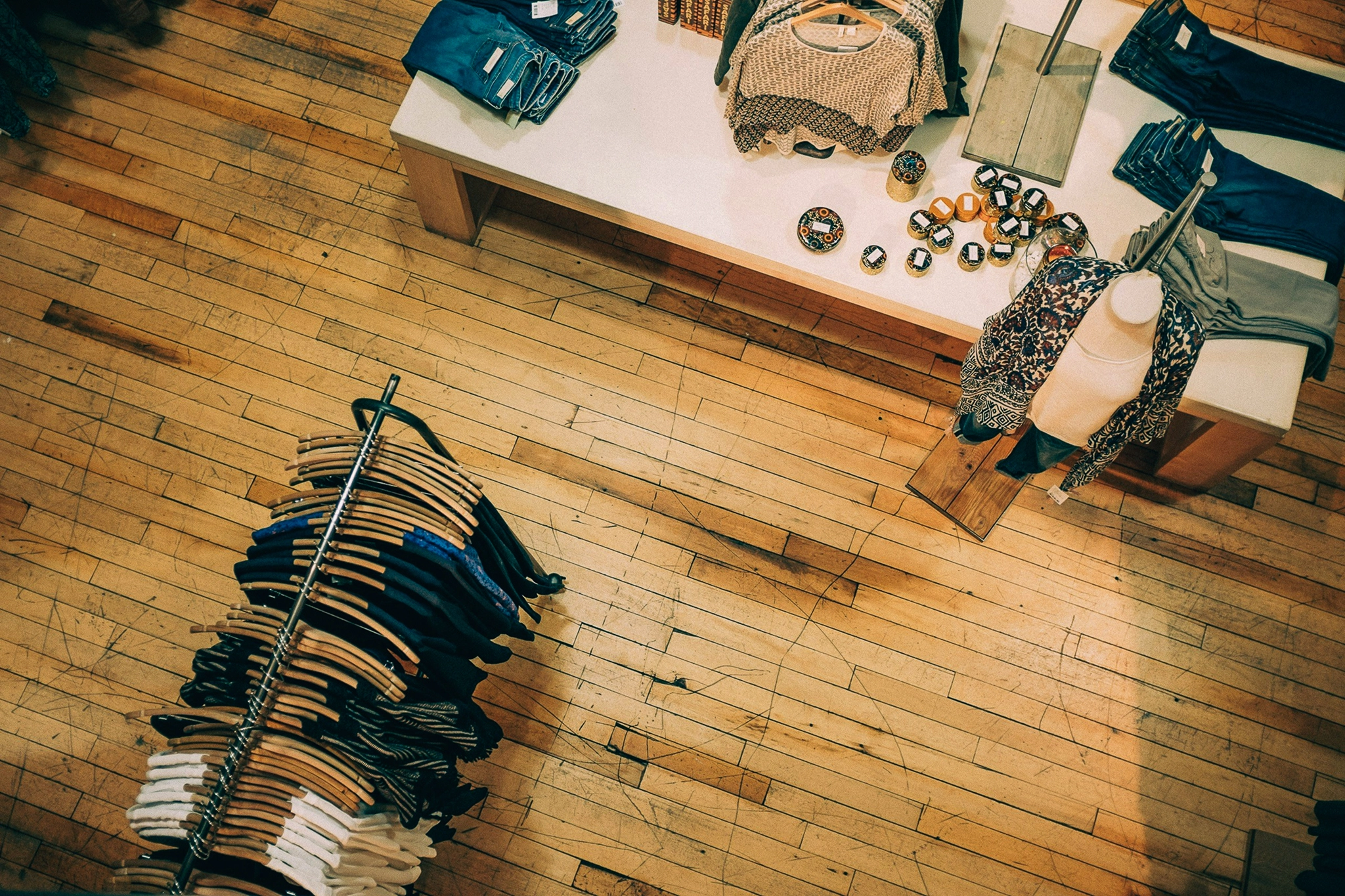 Overhead view of a small clothing boutique with merchandise on a rack and a table
