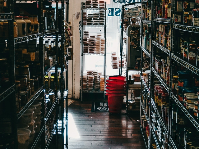 View from inside a small convenience store aisle looking through to the storefront window