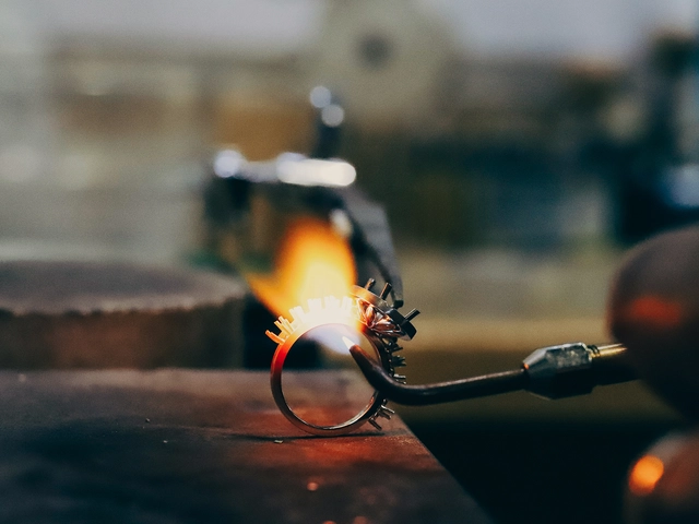 A metalsmith holds a blowtorch to a circle