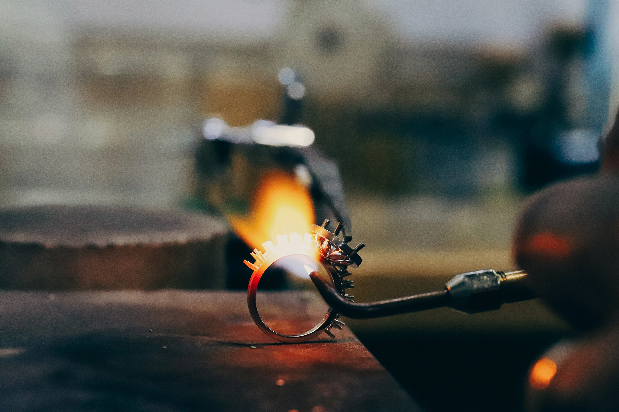 A metalsmith holds a blowtorch to a circle