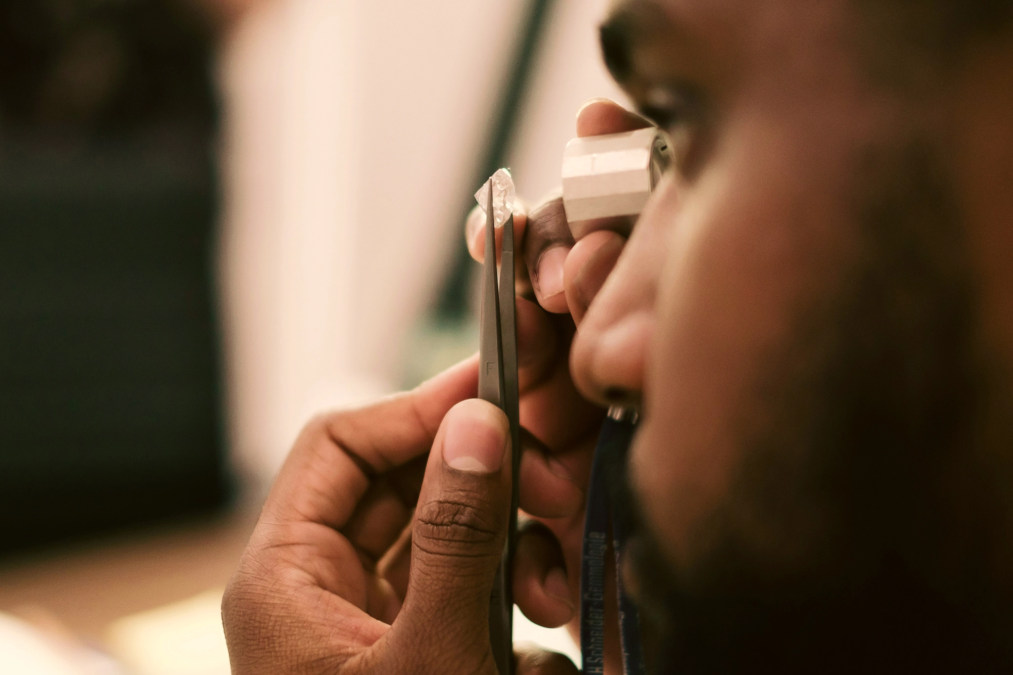 A jeweler inspects a gem through a jeweler's loupe