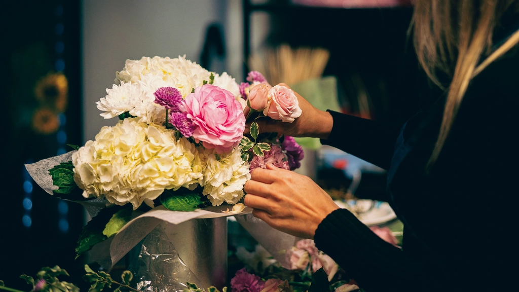 Hands arrange flowers in a vase