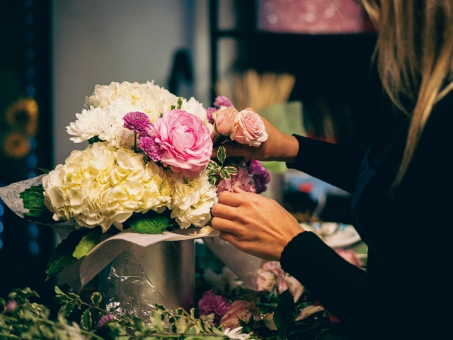 Hands arrange flowers in a vase