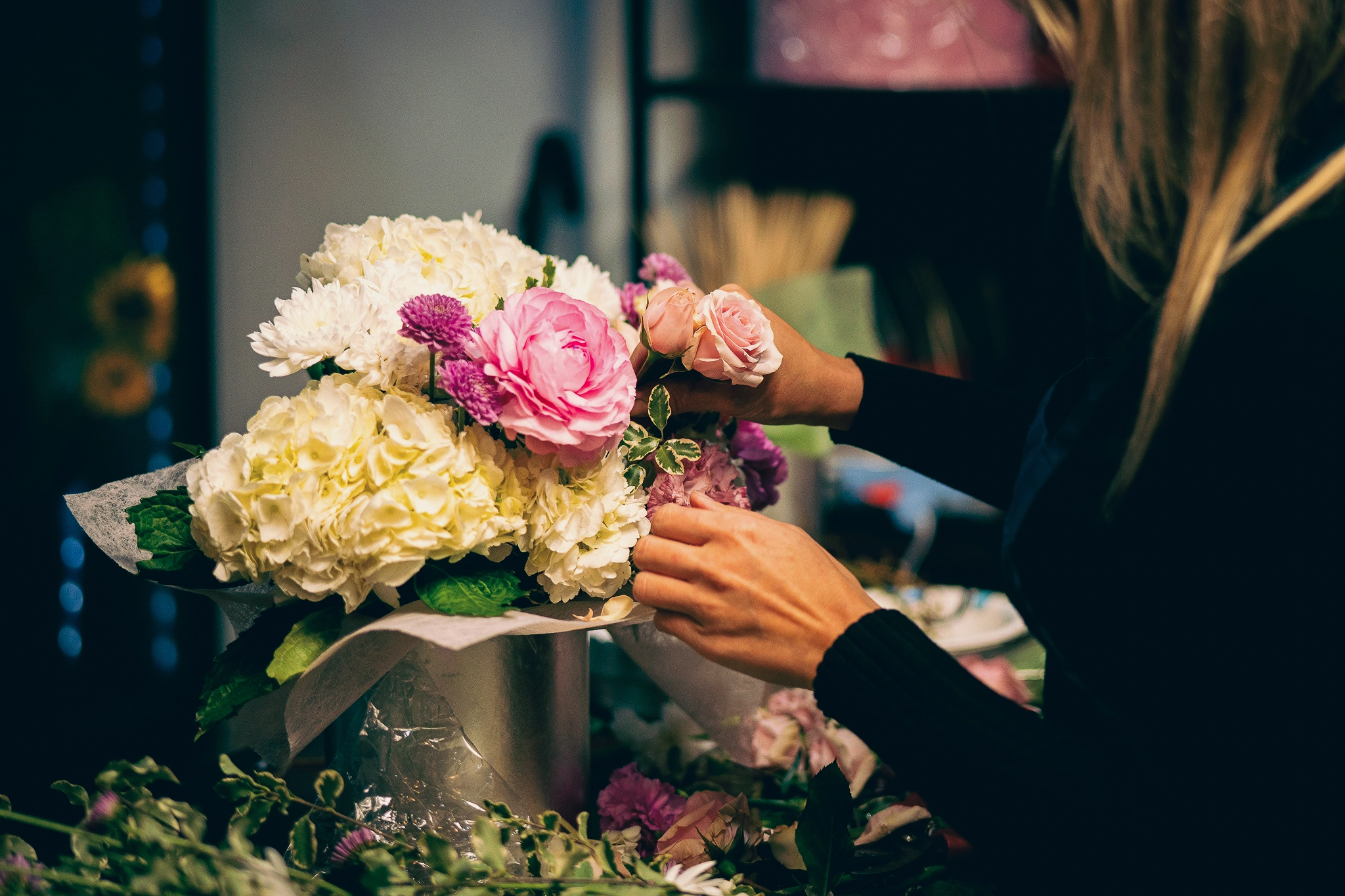 Hands arrange flowers in a vase
