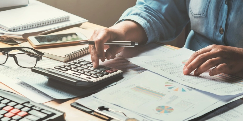 A desk with a small business owner looking over financial papers like invoices and receipts
