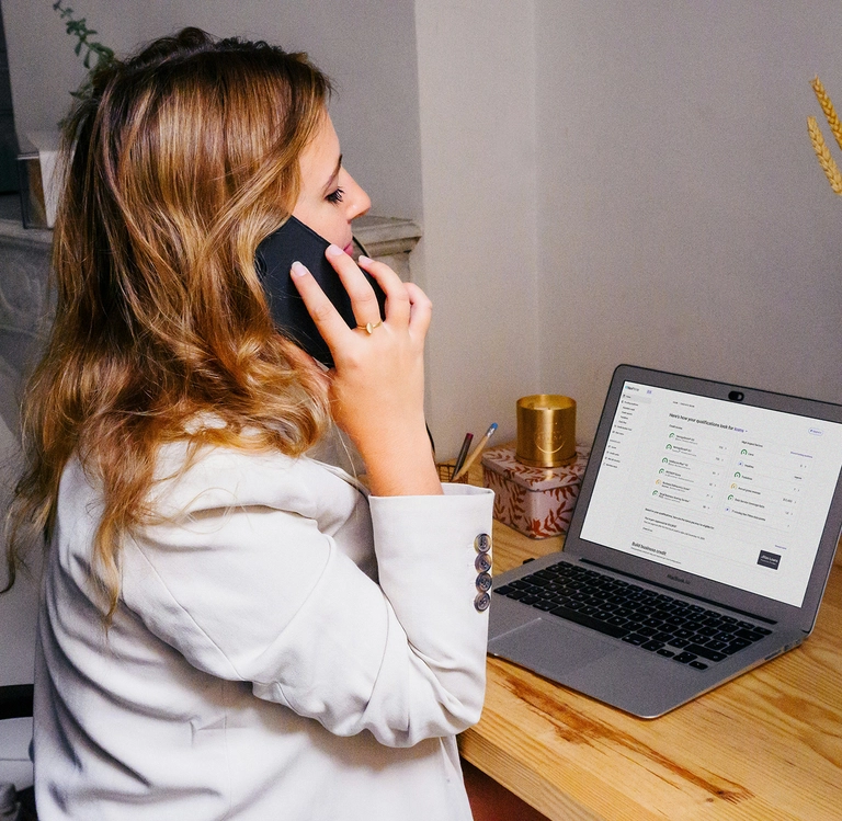 woman on the phone looking at her business finances talking to a business credit coach