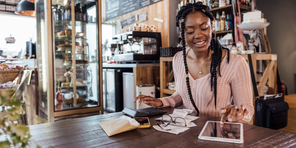 African American Woman small business owner sitting at a table in her coffee shop reviewing her cash flow and credit score