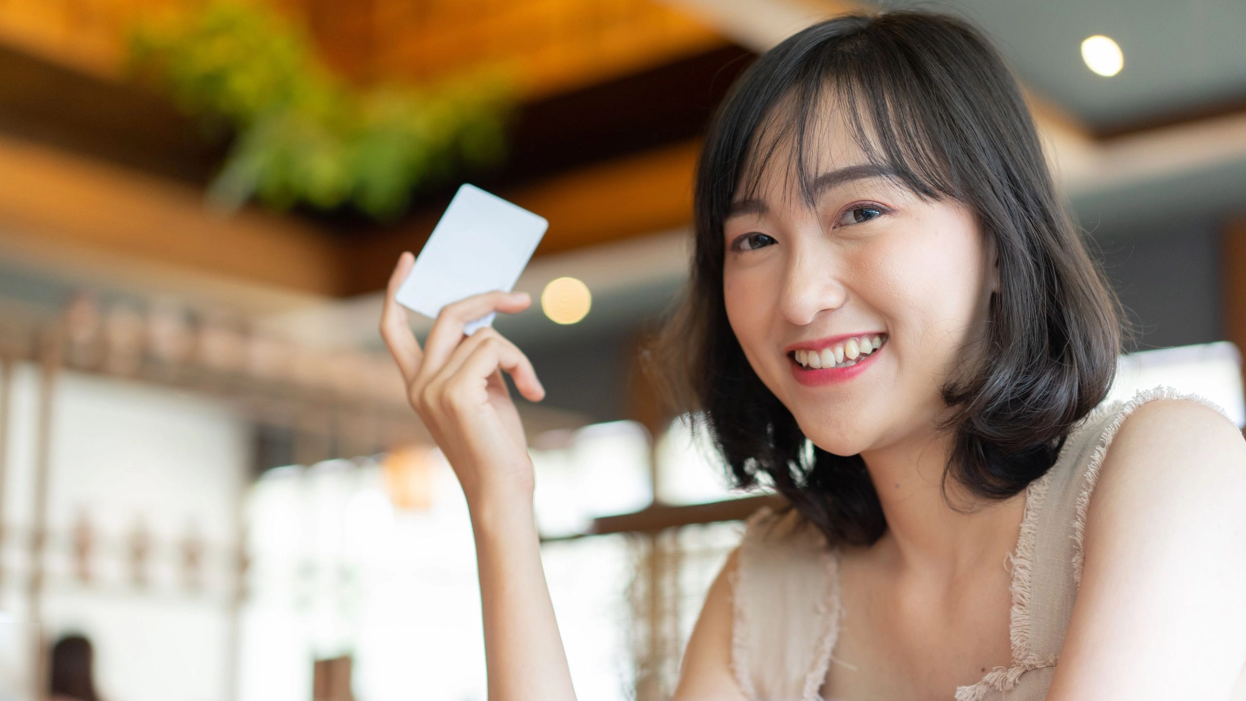Woman holding credit card to illustrate Stripe vs Square credit card processing