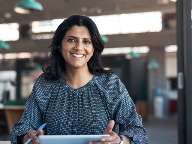 Business owner on tablet facing camera smiling to illustrate article about credit invisibles