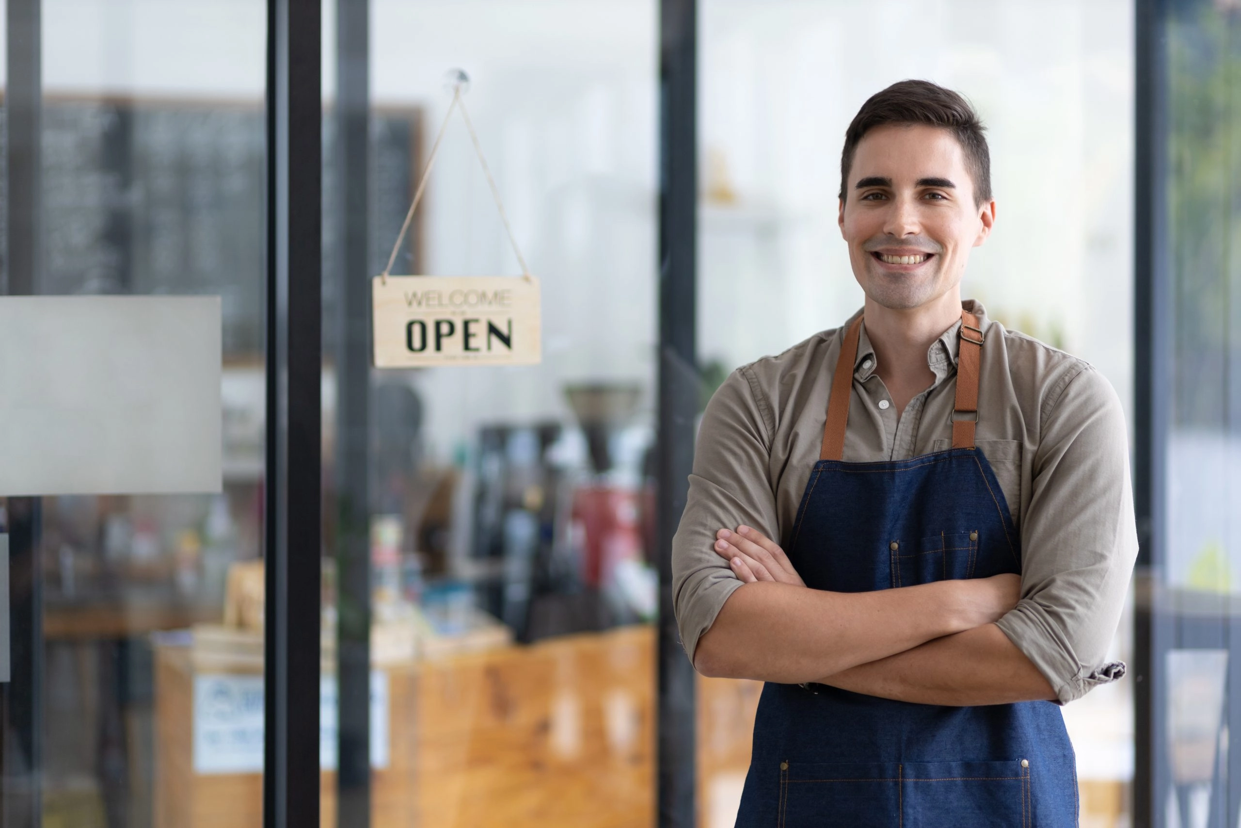 Entrepreneur standing in front of open sign meant to represent business owner cutting interest rates