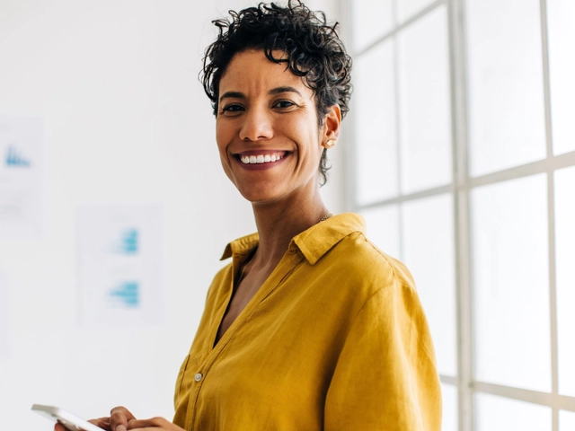 Woman smiling holding a cell phone to illustrate article about business credit monitoring
