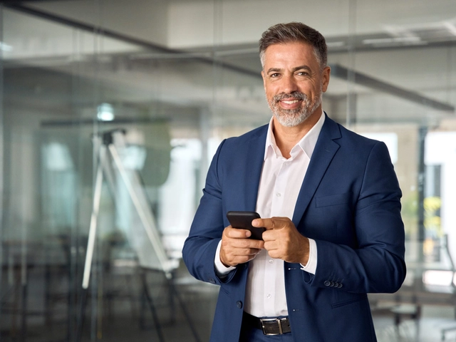 Male business owner in a blue suit smiling to illustrate article about business credit score factors.