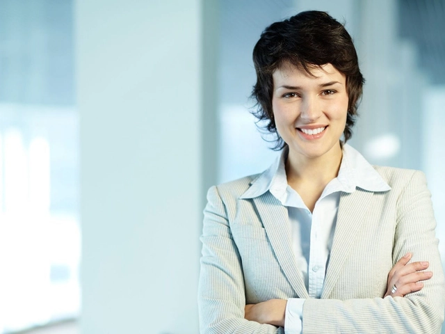 Business woman with short dark hair in light colored suit facing camera and with arms crossed to illustrate how banks assess credit risk.