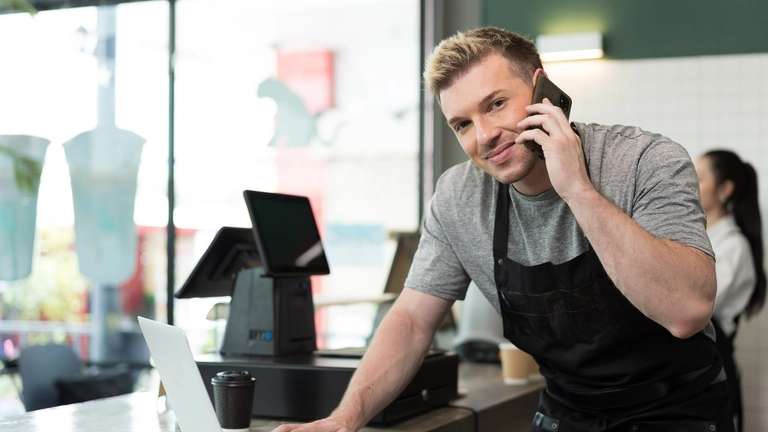 business owner on phone to illustrate freshbooks vs quickbooks