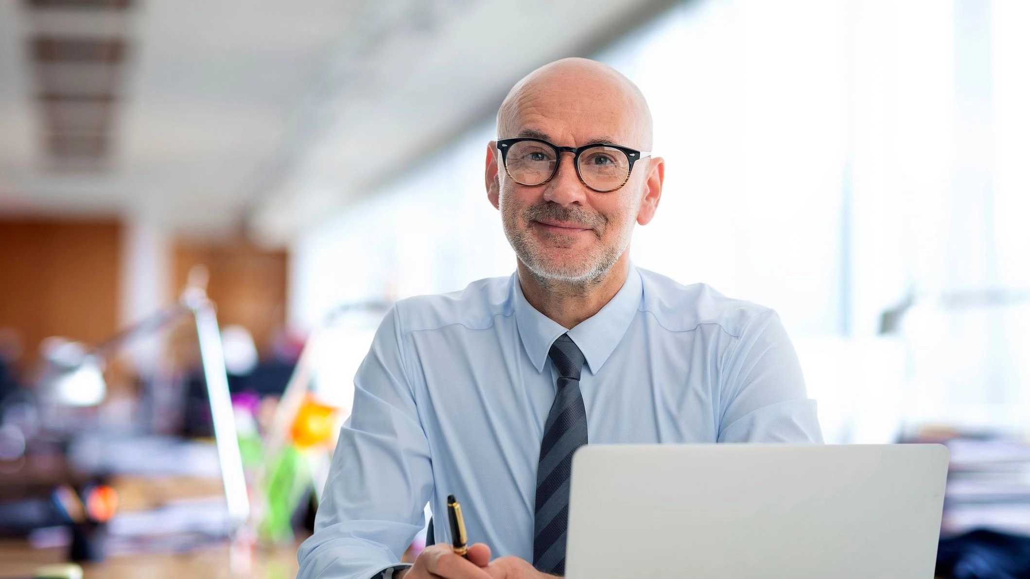 Business man in tie wearing glasses sitting at laptop to illustrate article about organizing business finances