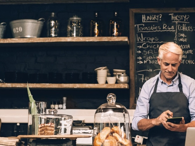 Man behind the counter at his small business doing calculations