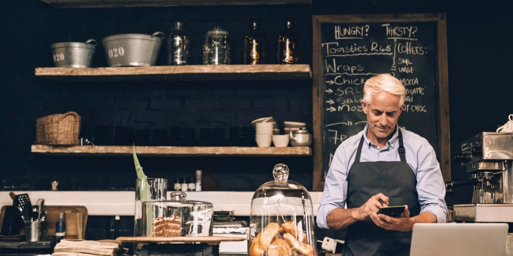 Man behind the counter at his small business doing calculations