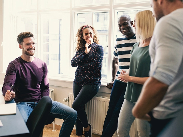 Small team of coworkers collaborating and talking in a bright office meeting space.
