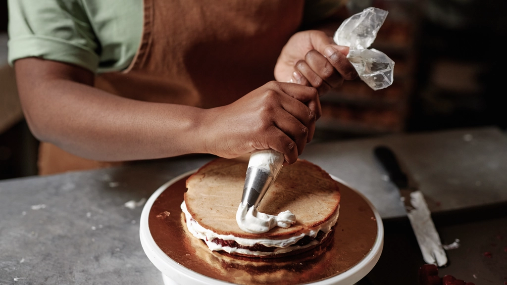 A person squeezes icing to decorate a cake