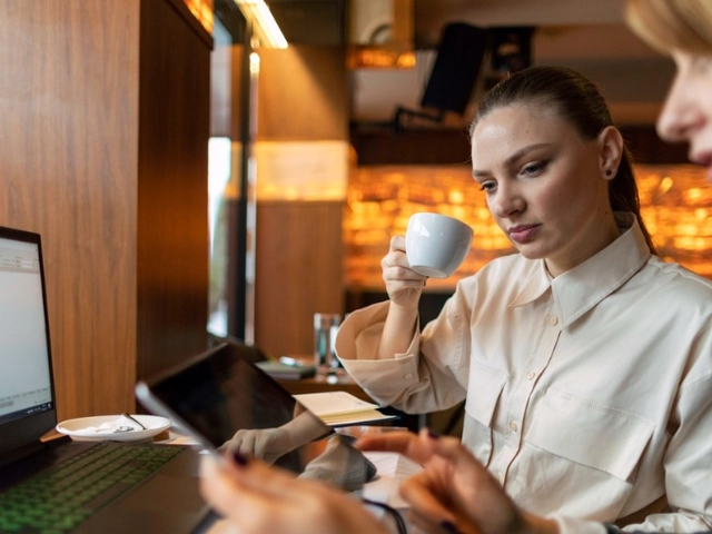 Two women reviewing expenses on a cell phone and paperwork