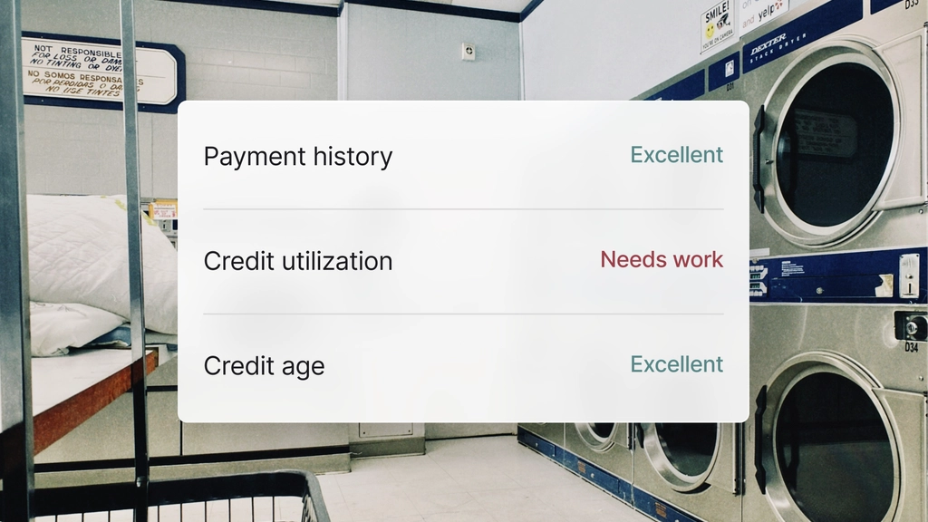 Credit health summary showing payment history as Excellent, credit utilization as Needs work, and credit age as Excellent over a background of a laundromat with industrial washers
