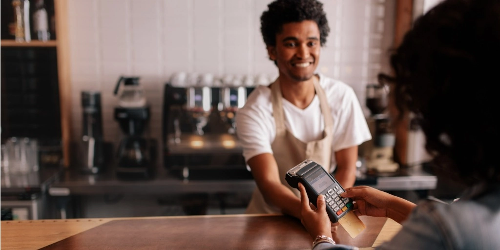 A young business owner accepts a credit card payment on a POS provided by a credit card processing company.